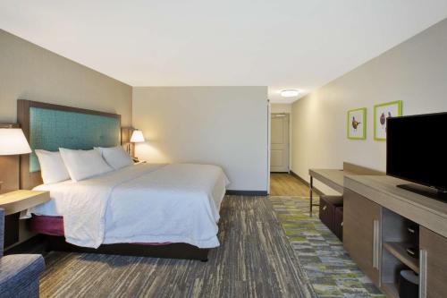 a hotel room with a bed and a flat screen tv at Hampton Inn & Suites By Hilton, Southwest Sioux Falls in Sioux Falls