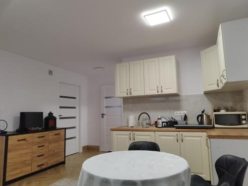 a kitchen with white cabinets and a white table at Piasecki Apartamenty in Lublin