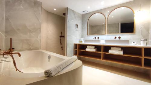 a bathroom with a tub and a sink at Hôtel La Plage 5 étoiles La Grande Motte in La Grande-Motte