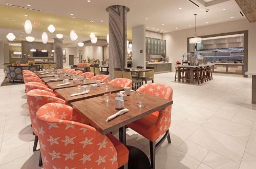 a restaurant with a long table and orange chairs at Hilton Garden Inn Ft. Walton Beach in Fort Walton Beach