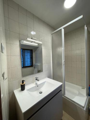 a white bathroom with a sink and a shower at Casa da Laurinha in Arcos de Valdevez