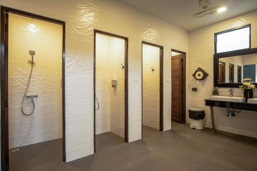 a bathroom with four shower stalls and a sink at Sea Beach Hostel & Club AoNang Beachfront in Ao Nang Beach