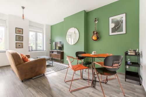 sala de estar con paredes verdes, mesa y sillas en Le Larsen, en Liévin