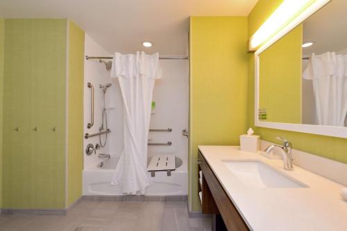 Home2 Suites By Hilton Merrillville في ميريلفيل: حمام مع حوض استحمام ودش ومغسلة