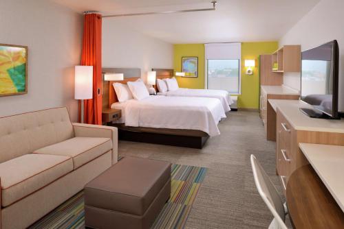 メリルビルにあるHome2 Suites By Hilton Merrillvilleのベッド2台とソファが備わるホテルルームです。