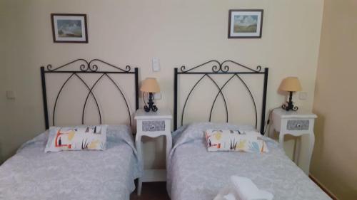 two beds in a room with two tables and two lamps at Fonda la Plaza in Valderrobres