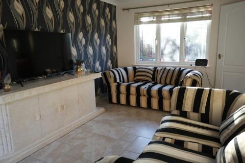 a living room with two couches and a flat screen tv at Cosy Stirling 3-bedroom Home in Stirling