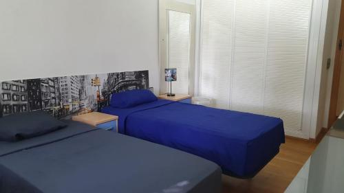 two beds in a bedroom with blue sheets at Casa Pinares in Móstoles