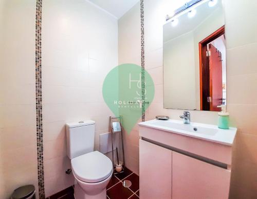 y baño con aseo, lavabo y espejo. en Penthouse Duplex Vista Marina T1 Ap por HsRentals en Vilamoura