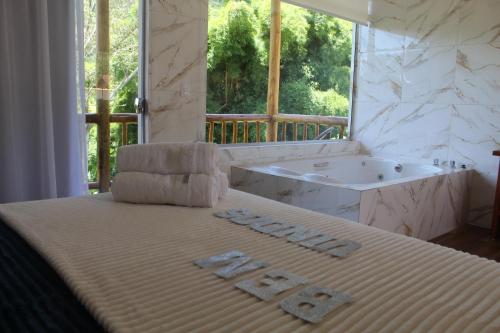 Schlafzimmer mit einem Bett mit einer Badewanne und einem Waschbecken in der Unterkunft Chales Maria Flor in Gonçalves