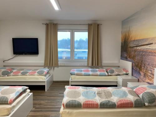 Zimmer mit 3 Betten und einem Flachbild-TV in der Unterkunft Boardinghouse am Steinkläffle in Friolzheim