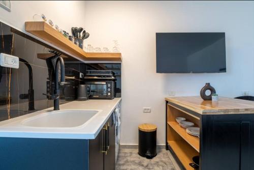 uma cozinha com um lavatório e uma televisão na parede em eve's room em Haifa
