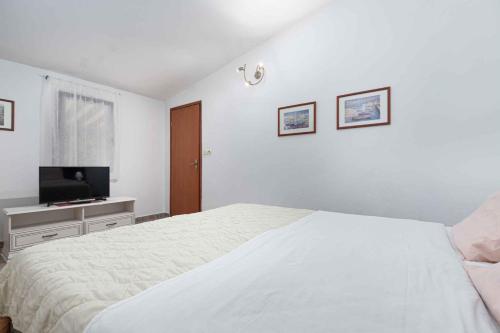a white bedroom with a bed and a flat screen tv at Apartment in Mugeba/Istrien 27611 in Mugeba