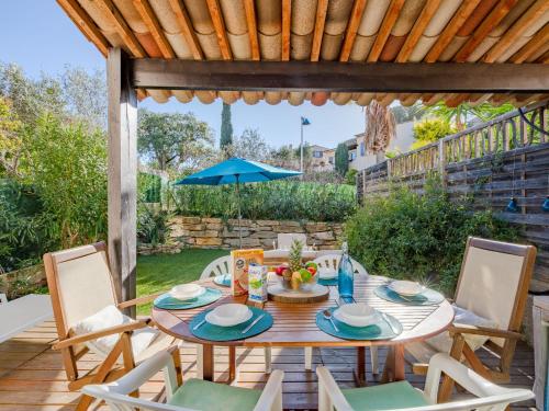 une table avec des chaises et un parasol sur une terrasse dans l'établissement Holiday Home Le Laurier by Interhome, à Le Plan