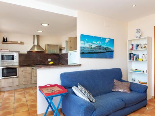 a living room with a blue couch and a kitchen at Apartment Codolar by Interhome in Tossa de Mar