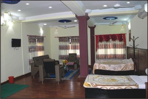 1 dormitorio con 2 camas y sala de estar con TV. en Siddhartha Guest House, en Rummindei