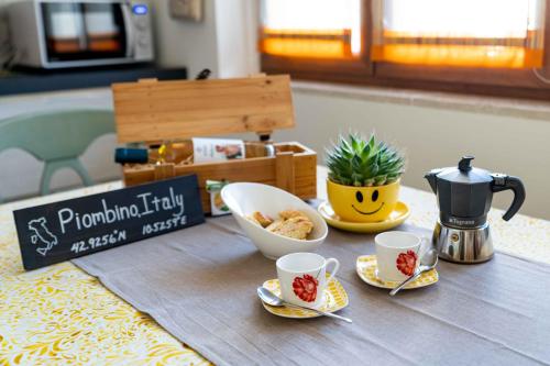a table with two cups of coffee and a bowl of food at sunny courtyard in Piombino
