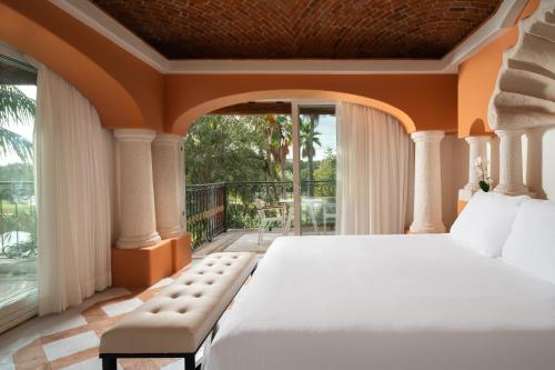 um quarto com uma cama grande e uma varanda em Eurostars Hacienda Vista Real em Playa del Carmen