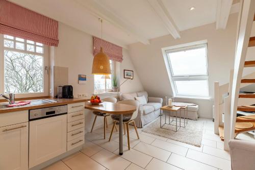 eine Küche und ein Wohnzimmer mit einem Tisch und einem Sofa in der Unterkunft Strandhafer im Haus Südstrand in Wyk auf Föhr