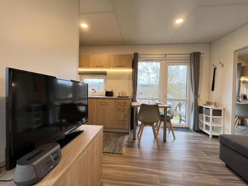 a living room with a large television and a kitchen at Holiday Home Tiny Haus mit schönem Seeblick by Interhome in Wemding
