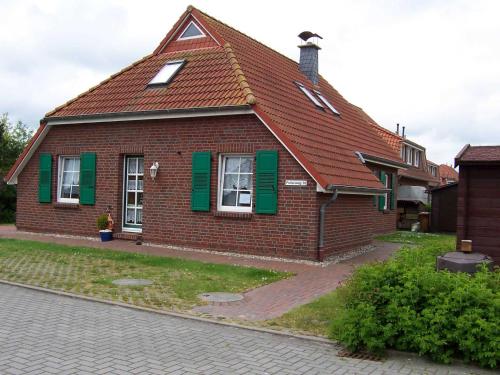 una piccola casa in mattoni rossi con persiane verdi di Ferienwohnungen Höhn ad Altfunnixsiel