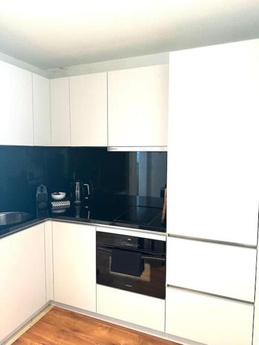 a kitchen with white cabinets and a black oven at Wonderful cosy apartment in St. Moritz in St. Moritz