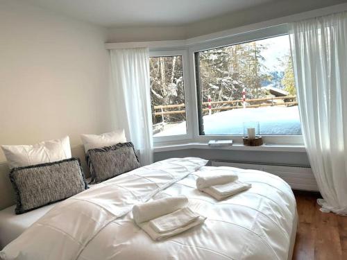 a bedroom with a large white bed with a window at Wonderful cosy apartment in St. Moritz in St. Moritz