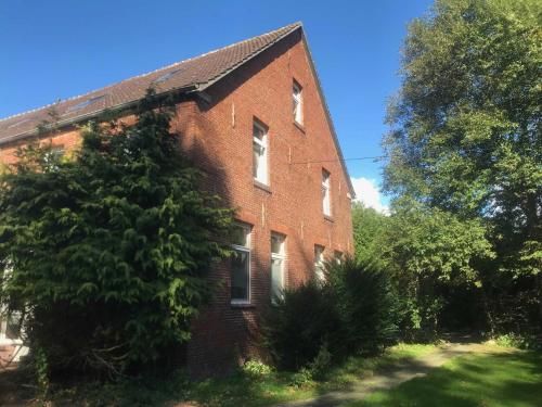 ein altes Backsteingebäude mit einem Baum davor in der Unterkunft Gulfhof Friedrichsgroden in Carolinensiel