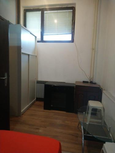 a room with a refrigerator and a table and a window at Stan Petrovac na Mlavi ( 10km od Banje Ždrelo ) in Petrovac na Mlavi