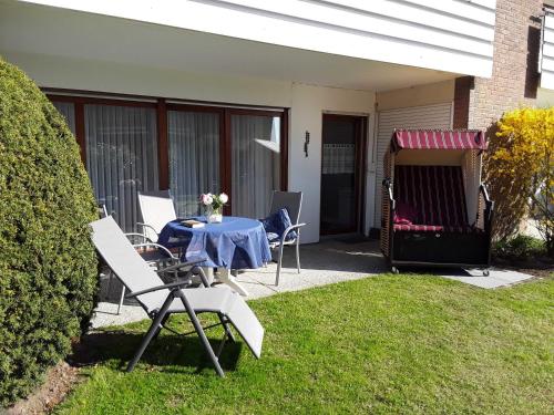 a patio with a table and chairs on the grass at Ferienwohnung Goldan Möwenweg in Carolinensiel