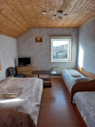 a room with two beds and a table and a window at Ginto nakvynės namai in Vilnius