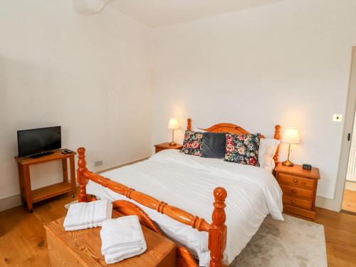 a bedroom with a wooden bed and a television at Natland Hall Cottage in Kendal