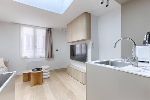 une cuisine blanche avec un évier et une table dans l'établissement MyKeypers - Luxury Design Flat 2BR/6P - Rue de Charonne !, à Paris