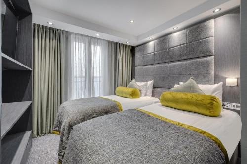 Habitación de hotel con 2 camas con almohadas amarillas en Mornington Hotel London Victoria, en Londres