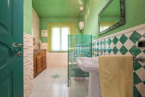 Baño verde con lavabo y espejo en Villa Gambula, en Carbonia