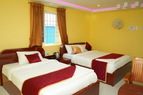 Duas camas num quarto com paredes amarelas em H2 Residency em Ramanathapuram