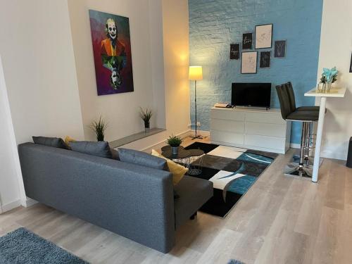 een woonkamer met een blauwe bank en een televisie bij FlatDeCologne CityPerle in Keulen