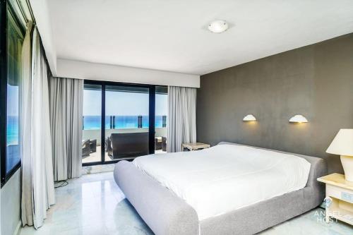sypialnia z białym łóżkiem i dużym oknem w obiekcie Fabulous Oceanview Suite with Private Jacuzzi plus Access to Beach&Pools w mieście Cancún