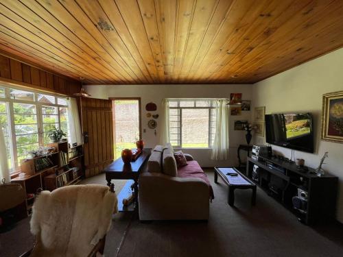 sala de estar con sofá y techo de madera en Casa aconchegante próximo ao Capivari, en Campos do Jordão