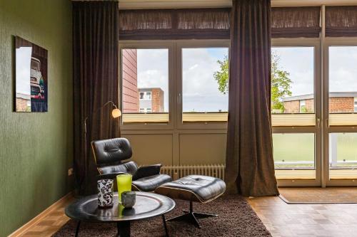 - un salon avec une chaise, une table et une fenêtre dans l'établissement Uthlande-Strandhafer, à Wyk auf Föhr