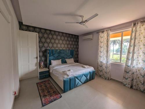 ein Schlafzimmer mit einem blauen Bett und einem Fenster in der Unterkunft Sandy toes 2 bhk facing paddy field , pool available and walking distance to beach in Varca