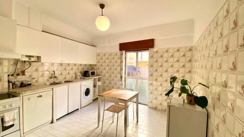 リスボンにあるChiado Apartment with Terrace 1の白いキャビネットとテーブル付きのキッチンが備わります。