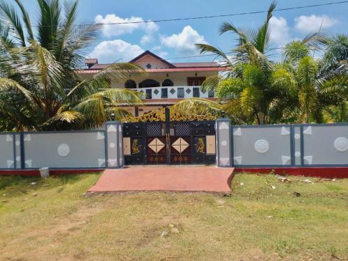 a gate in front of a house with palm trees at Nedunkerniy Sri Lanka 