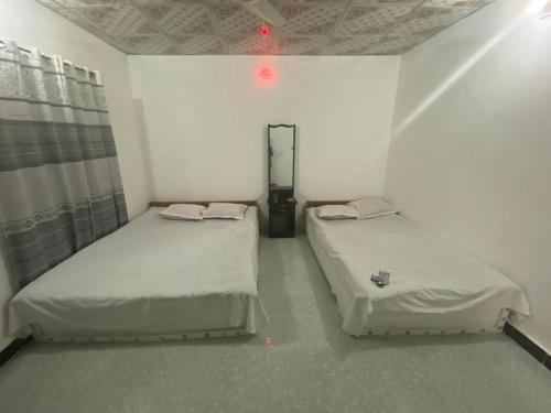 2 camas en una habitación pequeña con luz roja en Surjasto Resort, en Jaliapāra
