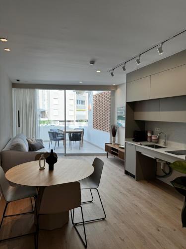 a kitchen and a living room with a table in a room at Reyes Católicos Premium Beach, Playa Urbanova, Alicante in Alicante