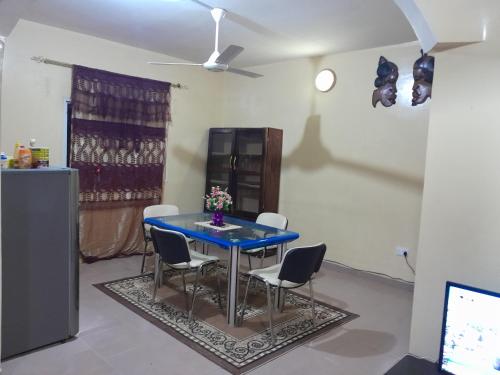 a dining room with a blue table and chairs at Fayes Apartments in Brusubi