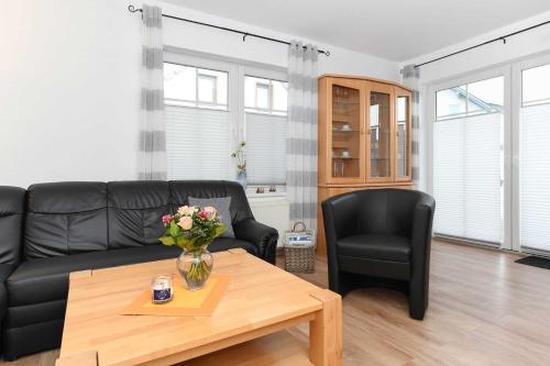 Una sala de estar con un sofá negro y una mesa. en Ferienwohnung Möwe, en Carolinensiel