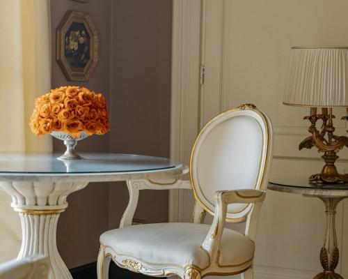 a table and a chair with a vase on it at Grand Hotel Tremezzo in Tremezzo