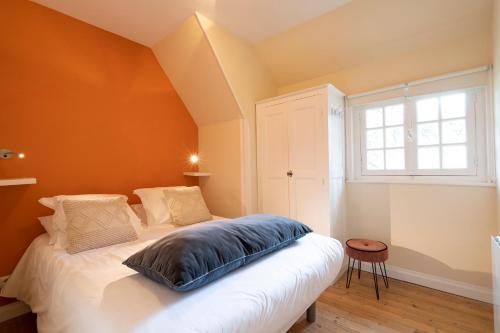a bedroom with a white bed with an orange wall at Demeure d'Hôtes Haec Otia in Le Touquet-Paris-Plage