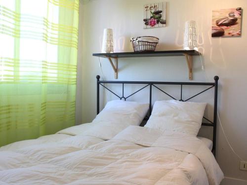 - un lit avec des oreillers blancs et une étagère sur le mur dans l'établissement Appartement front de mer à La Baule : T2 avec terrasse, parking et Wifi - FR-1-245-120, à La Baule